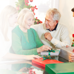 Family celebrating the holidays together as an older couple exchanges gifts with adult children